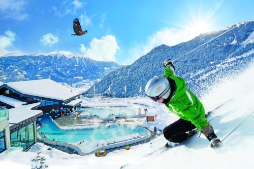 a person on skis in the snow next to a resort at Hôtel Les Bains d'Ovronnaz in Ovronnaz