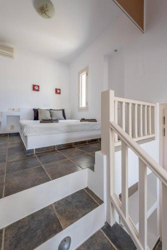 a white bedroom with a bed and a staircase at Mylopota apartment IV in Ios Chora