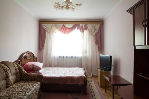 a bedroom with a bed and a couch and a window at Apartament Sanitarna 17 in Lviv