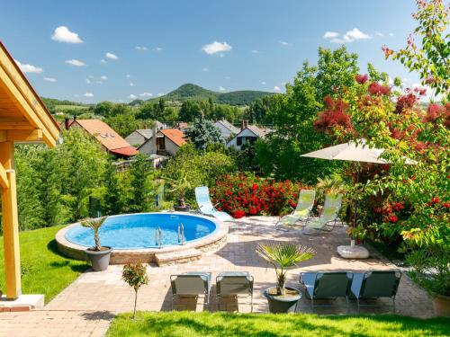 a swimming pool in a yard with chairs and an umbrella at Apartment Beate by Interhome in Badacsonytomaj