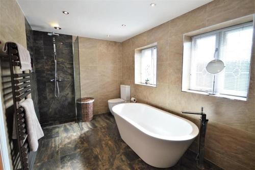 a bathroom with a tub and a shower and a toilet at Lavish4Bed Mansion in Warrington in Warrington