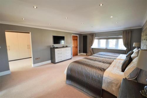 a large bedroom with a large bed and a television at Lavish4Bed Mansion in Warrington in Warrington