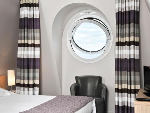 - une chambre avec une chaise et une fenêtre ronde dans l'établissement Apartment Villas du Spa-4 by Interhome, à Pléneuf-Val-André