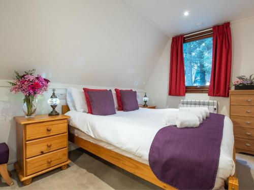 a bedroom with a large bed and red curtains at Chalet Lodge 26 by Interhome in Spean Bridge