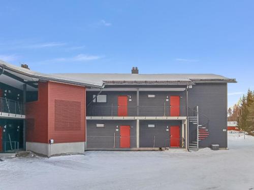 a building with red doors in a parking lot at Holiday Home Levistar vi as- 6108 by Interhome in Levi