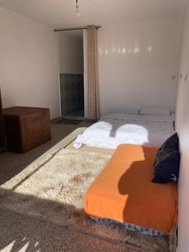 two beds in a bedroom with an orange mattress at room in tamraght - 10min walk to the beach in Aourir