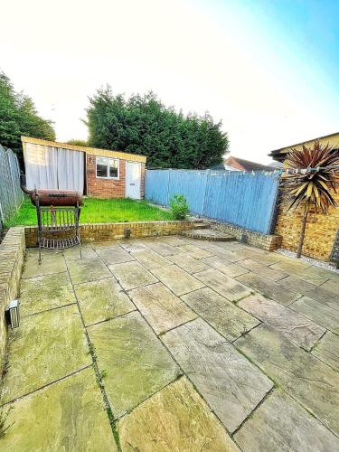 a patio with a bench and a blue fence at Modern 3 Bed House In Essex By DLuxoria Short Lets & Serviced Accommodation With Pet Friendly, Free WiFi & Free Parking in Basildon