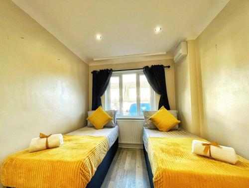 two beds in a room with yellow sheets and a window at Modern 3 Bed House In Essex By DLuxoria Short Lets & Serviced Accommodation With Pet Friendly, Free WiFi & Free Parking in Basildon