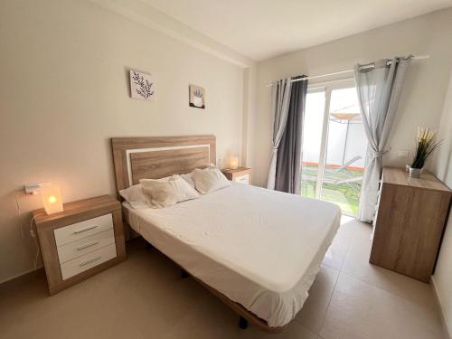 a bedroom with a bed with white sheets and a window at Villa Majunaxa in Corralejo