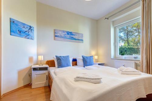 une chambre avec un grand lit blanc avec des oreillers bleus dans l'établissement Haus Berlin Loddiner Höft, à Loddin