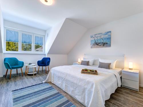 1 dormitorio blanco con 1 cama y 2 sillas azules en Bernsteinquartier BQ 07e - Ferienhaus Meerzeit, en Kolpinsee