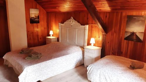 two beds in a bedroom with wooden walls and wooden floors at Confortable chalet au calme à l'étang du stock in Langatte