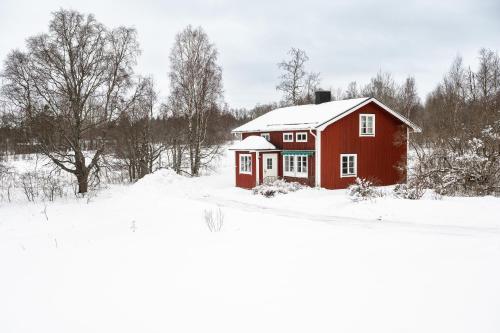a red barn with snow on it in a field at Gasabäck Holiday Accomondation in Söråker