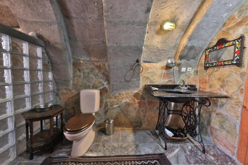 a stone bathroom with a toilet and a sink at Potamia Cave Suites in Ortahisar
