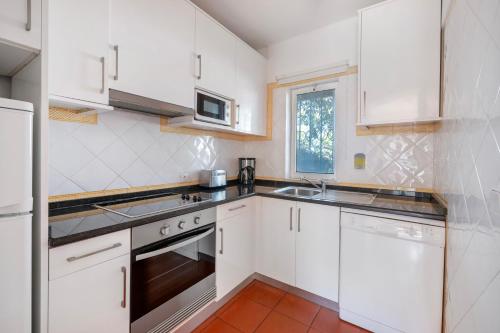 a white kitchen with white cabinets and a sink at Vilar do Golf in Quinta do Lago