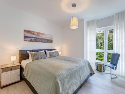 ein Schlafzimmer mit einem Bett, einem Stuhl und einem Fenster in der Unterkunft Bernsteinquartier BQ 0558 - Eichenkrone in Ostseebad Kölpinsee