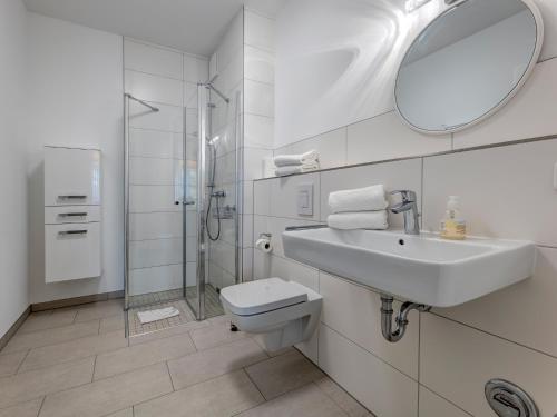 ein Badezimmer mit Waschbecken, Toilette und Spiegel in der Unterkunft Bernsteinquartier BQ 0558 - Eichenkrone in Ostseebad Kölpinsee