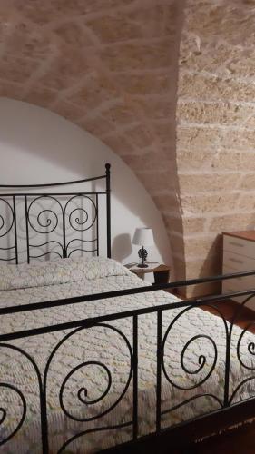 a bedroom with a black bed with a stone wall at residence specchia in Specchia
