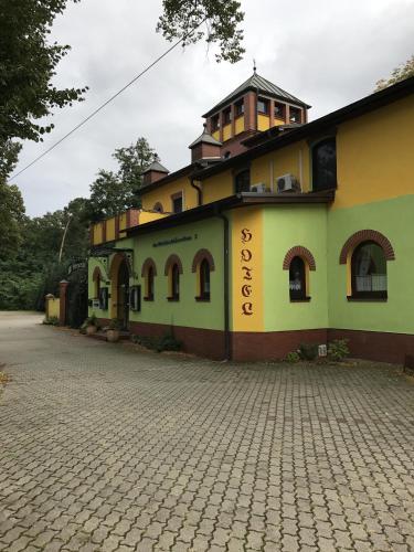 ein gelbes und grünes Gebäude mit einem Turm oben in der Unterkunft Waldschlösschen in Mittenwalde