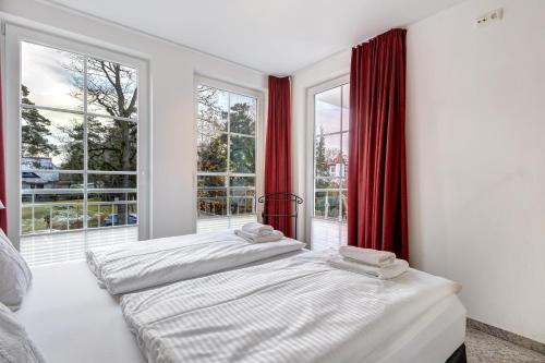 two beds in a room with windows and red curtains at Ostseeresidenz Gorki- Park - 07 mit Wellness und Schwimmbad in Bansin