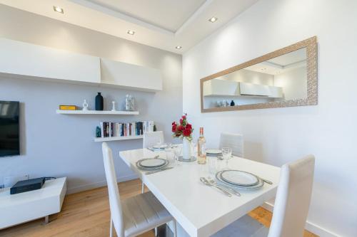 une salle à manger blanche avec une table blanche et un miroir dans l'établissement Air-Conditioned 2-Br Apartment with Garage Near the Beach, à Cannes