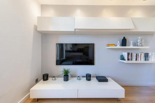 Cette chambre comprend une table blanche et une télévision murale. dans l'établissement Air-Conditioned 2-Br Apartment with Garage Near the Beach, à Cannes