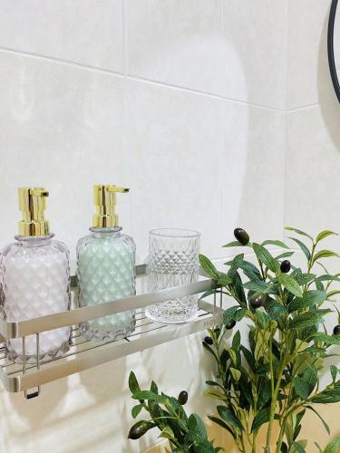 a shelf with two bottles and glasses and a plant at The Cozy Lazy Home Hatyai in Hat Yai