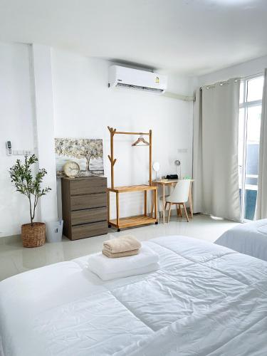 a white bedroom with a large bed and a table at The Cozy Lazy Home Hatyai in Hat Yai