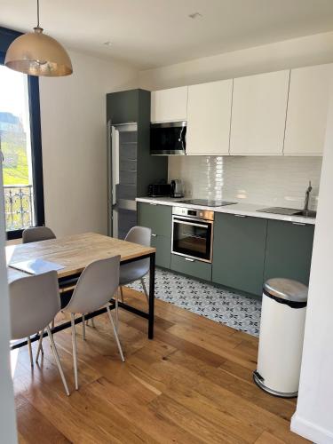une cuisine avec une table en bois et des armoires blanches dans l'établissement Maison vue mer proche Deauville et plage, à Benerville-sur-Mer