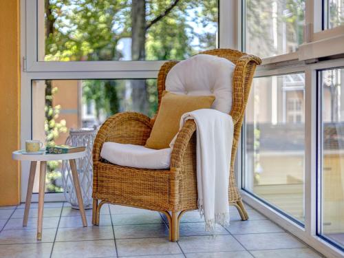 une chaise en osier assise sur une terrasse couverte à côté d'une fenêtre dans l'établissement Ostseepark Waterfront Karavelle Wohnung 3.5, à Bansin