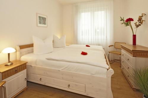 a bedroom with a white bed with red flowers on it at Residenz Waldhaus_05 in Zempin