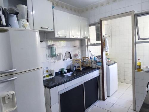 a white kitchen with a sink and a refrigerator at Apto 2 quartos em frente à praça nova do Imbui Excelente localização in Salvador