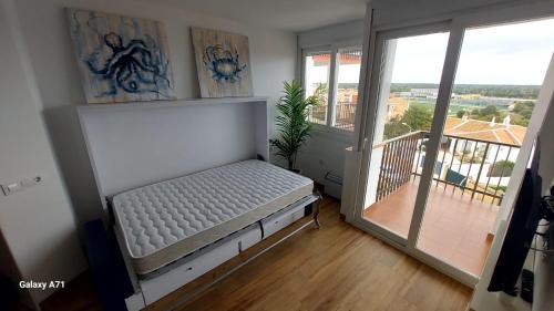 a bed in a room with a balcony at Apartamento con piscina in Matalascañas