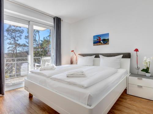 Villa Strandperle Wohnung 28/29 Bansin في بانسين: غرفة نوم بيضاء مع سرير كبير ونافذة