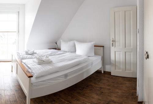 un lit blanc avec des draps blancs et des oreillers blancs dans l'établissement Meerferienhaus - Haus Schlehenweg, à Zinnowitz