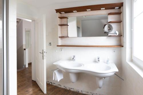 une salle de bain blanche avec un lavabo et un miroir dans l'établissement Meerferienhaus - Haus Schlehenweg, à Zinnowitz