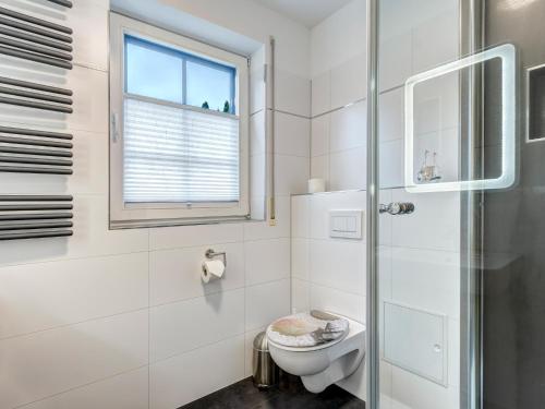 a white bathroom with a toilet and a window at Haus Sonnenschein FeWo Seepferdchen in Trassenheide