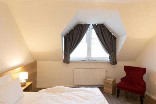 a bedroom with a window and a red chair at Cuxlandhotel Doppelzimmer 115 in Dorum Neufeld