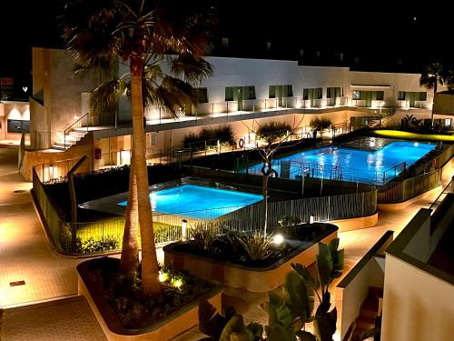 un edificio de apartamentos con 2 piscinas y una palmera en Lovely New Luxery Beach Apartment in Mojacar Playa next to the best beach, en Mojácar