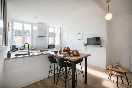 - une cuisine blanche avec une table en bois et un comptoir dans l'établissement Séjour de Charme T3 Centre Historique Bergerac, à Bergerac