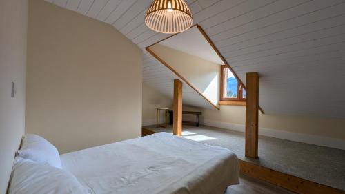 une chambre mansardée avec un lit et une fenêtre dans l'établissement Immeuble Savonette, au Bourg-dʼOisans