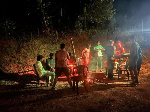 a group of people standing around a fire at night at Serenehills Retreat in Idukki