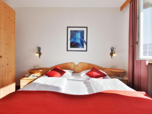 a bedroom with a large white bed with red pillows at Apartment Residence Egger - n-102 by Interhome in Villandro