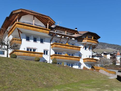 a white building with wooden balconies on a hill at Apartment Residence Egger - n-102 by Interhome in Villandro