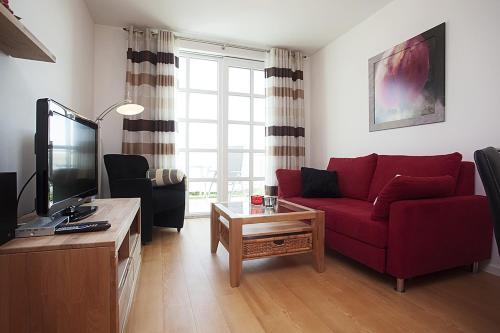 a living room with a red couch and a tv at Residenz am Balmer See - BS 01 mit Wellnessbereich in Balm
