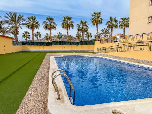 una piscina en medio de un edificio con palmeras en Apartamento con Terraza, Piscina y Parking By Aloha Palma, en Águilas