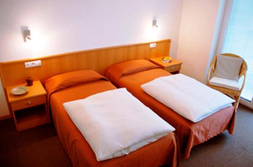 a hotel room with two beds and a chair at Garni Cremona in Bressanone