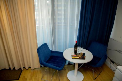 a white table and blue chairs in a room with a window at Orbi city - Premium Class Rooms N1 in Batumi