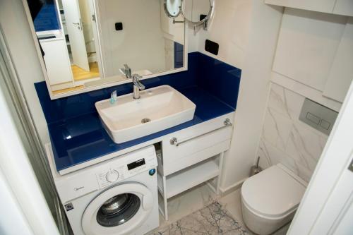 a bathroom with a sink and a washing machine at Orbi city - Premium Class Rooms N1 in Batumi