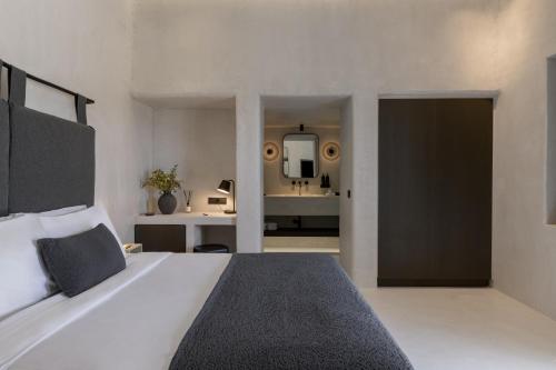 a bedroom with a large bed and a bathroom at Rocabella Mykonos Hotel in Agios Stefanos
